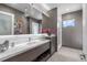 Modern bathroom with a grey vanity, a large mirror, textured walls and a glass shower at 5131 W Neptune Way, Tampa, FL 33609