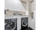 Modern laundry room features front loading washer and dryer, white countertops, and cabinets for ample storage at 5131 W Neptune Way, Tampa, FL 33609