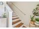Bright stairway featuring wood treads, white risers, and a handrail at 542 Black Lion Ne Dr, St Petersburg, FL 33716