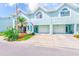 Charming townhome featuring a two-car garage, lush landscaping, and a welcoming entrance at 615 Garland Cir, Indian Rocks Beach, FL 33785