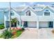 Charming light blue townhouse with a one-car garage, nice landscaping and a visible American flag at 615 Garland Cir, Indian Rocks Beach, FL 33785