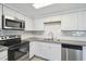 Close up of stainless steel appliances, granite countertops and white cabinets at 6235 Viola Ln, New Port Richey, FL 34653