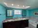 Bright bathroom featuring double sinks with granite countertops, a skylight, and marble tile accents at 6319 Cocoa Ln, Apollo Beach, FL 33572