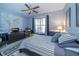 Comfortable bedroom featuring a ceiling fan, striped bedding, and a large window for natural light at 6448 Country Club Rd, Wesley Chapel, FL 33544