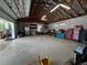 Spacious garage featuring an open ceiling with wooden beams and lots of space for tools and projects at 6448 Country Club Rd, Wesley Chapel, FL 33544