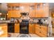 Well-equipped kitchen featuring wooden cabinets, granite countertops, black appliances and tile backsplash at 6448 Country Club Rd, Wesley Chapel, FL 33544