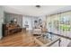 Spacious living room featuring hardwood floors, piano, and a cozy chair with natural light shining through large windows at 6667 28Th S St, St Petersburg, FL 33712