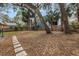 Backyard with a hammock, mature trees, and a stone pathway, perfect for outdoor relaxation at 7819 Chasco St, Port Richey, FL 34668