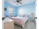 Bedroom with bright blue walls, a window with blinds, and a pink patterned quilt at 810 W Whatley Pl, Tampa, FL 33604