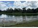 Picturesque pond view framed by a white picket fence, showcasing a serene natural landscape at 10108 36Th E Ct, Parrish, FL 34219