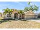 Charming single-story home featuring a three car garage, lush landscaping and mature palm trees enhancing curb appeal at 12519 Safari Ln, Riverview, FL 33579
