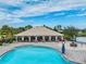 Community pool and splash pad with a covered seating area, surrounded by palm trees and lounge chairs at 12519 Safari Ln, Riverview, FL 33579