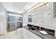 Bathroom with glass enclosed shower, black countertop and a large mirror at 13850 Sunset Dr, Largo, FL 33774