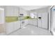 Bright kitchen featuring white cabinets, appliances, and tile floors with a glass door to outside at 13850 Sunset Dr, Largo, FL 33774