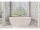 Modern white soaking tub positioned near a large window with blinds and marble tile floors at 16121 Carencia Ln, Odessa, FL 33556