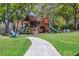 Wooden playground with slides, climbing wall, and swings surrounded by lush landscaping and grass at 16121 Carencia Ln, Odessa, FL 33556