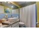 This bathroom boasts blue tile accents, a modern vessel sink, and a shower curtain for a fresh and clean feel at 1847 Shore Drive South # 308, South Pasadena, FL 33707