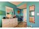 This bedroom features a bright blue wall, a decorative mirror, and a white dresser with seashell-shaped knobs at 1847 Shore Drive South # 308, South Pasadena, FL 33707