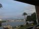 Scenic water view from a window, featuring a palm tree, dock, and distant city lights at 1847 Shore Drive South # 308, South Pasadena, FL 33707
