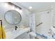 Updated bathroom featuring a vanity, modern round mirror, tub with shower, and nautical decor at 1851 Glenville Dr, Clearwater, FL 33765
