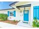 Charming home entrance with a blue front door, decorative accents, and lush landscaping at 1851 Glenville Dr, Clearwater, FL 33765