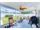 Relaxing screened-in porch with seating, ceiling fan, and view of the fenced-in backyard at 1851 Glenville Dr, Clearwater, FL 33765