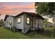 Quaint home featuring a small porch, white siding, and dark trim, set against a vibrant sunset sky at 2920 E 20Th Ave, Tampa, FL 33605