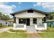 Charming home with a black door, white porch railing, gray stairs, and lush front lawn at 2920 E 20Th Ave, Tampa, FL 33605