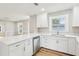 Bright kitchen features white cabinets, quartz countertops, stainless dishwasher and wood-look flooring at 2920 E 20Th Ave, Tampa, FL 33605