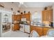 Functional kitchen with wooden cabinets, light countertops, white appliances, and an adjacent breakfast nook at 3254 Lori Ln, New Port Richey, FL 34655