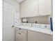 Laundry room features modern washer and dryer with white cabinets, as well as a hanging rack at 3254 Lori Ln, New Port Richey, FL 34655