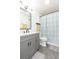 Bathroom with stylish gray vanity, toilet, shower/tub combination, and a modern floral-patterned shower curtain at 3502 Bloomingdale Ave, Valrico, FL 33596