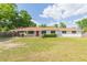Charming single-story home featuring a bright red door, carport, and a spacious front yard with mature trees at 3502 Bloomingdale Ave, Valrico, FL 33596