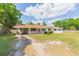Charming single-story home featuring a bright red door, carport, and a spacious front yard with mature trees at 3502 Bloomingdale Ave, Valrico, FL 33596