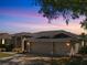 Twilight view of the home showing a three-car garage and manicured landscaping at 4301 Ridgemoor N Dr, Palm Harbor, FL 34685