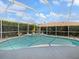 A beautiful screened-in pool with an adjacent spa and lush green foliage beyond at 4301 Ridgemoor N Dr, Palm Harbor, FL 34685