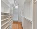 An ample walk-in closet with hardwood floors, bright white shelving, and track lighting at 4301 Ridgemoor N Dr, Palm Harbor, FL 34685