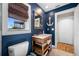 Bathroom showcases dark blue walls, a wooden vanity, white trim, and wood look floors at 4803 Longwater Way, Tampa, FL 33615