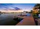 Modern boat dock with a boat lift, illuminated lighting, and picturesque waterfront views at dusk at 4803 Longwater Way, Tampa, FL 33615