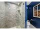 Tiled shower with a glass door, complemented by a toilet and blue wall with a decorative window at 4803 Longwater Way, Tampa, FL 33615