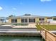 Backyard view of a yellow home with a pool and dock on a sunny day at 512 173Rd E Ave, North Redington Beach, FL 33708