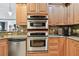 Modern kitchen featuring stainless steel appliances, granite countertops, stone backsplash, and wood cabinets at 525 Mandalay Ave # 33, Clearwater Beach, FL 33767