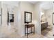 Hallway featuring travertine flooring, a decorative table with a mirror, and a view of the nearby bathroom at 5812 Mariners Watch Dr, Tampa, FL 33615