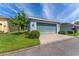 Light blue single-story home featuring an attached garage, concrete driveway, green lawn, and trimmed landscaping at 6111 Hadley Commons Dr, Riverview, FL 33578