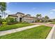 Charming home featuring a tile roof, brick driveway, and a well-manicured lawn at 8725 Sorano Villa Dr, Tampa, FL 33647