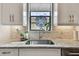 Bright kitchen featuring granite counters, a stainless steel sink, tile backsplash and a colorful stained glass window hanging at 8725 Sorano Villa Dr, Tampa, FL 33647