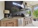 Well-equipped outdoor kitchen area with stainless steel grill, wooden cabinetry and concrete countertops at 8725 Sorano Villa Dr, Tampa, FL 33647
