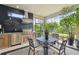 Covered patio with an outdoor kitchen, dining table, and lush landscaping, perfect for al fresco dining and entertaining at 8725 Sorano Villa Dr, Tampa, FL 33647