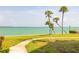 Serene waterfront view with lush green lawn, sidewalk, and swaying palm trees at 103 1St E St # 115, Tierra Verde, FL 33715