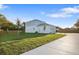 View of the backyard with a large concrete driveway, green grass, and a partial view of the two-story house at 11598 Oak Ln, Largo, FL 33778